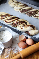 braid with chocolate, raw dough for a bun with chocolate. Freshly baked chocolate swirl pastry - babka. Baker make buns from dough with poppy and chocolate filling. Cooking twisted pie. Top view