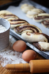 braid with chocolate, raw dough for a bun with chocolate. Freshly baked chocolate swirl pastry - babka. Baker make buns from dough with poppy and chocolate filling. Cooking twisted pie. Top view