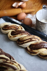 braid with chocolate, raw dough for a bun with chocolate. Freshly baked chocolate swirl pastry - babka. Baker make buns from dough with poppy and chocolate filling. Cooking twisted pie. Top view