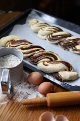 braid with chocolate, raw dough for a bun with chocolate. Freshly baked chocolate swirl pastry - babka. Baker make buns from dough with poppy and chocolate filling. Cooking twisted pie. Top view