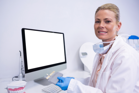 Portrait of dentist working while sitting by computer