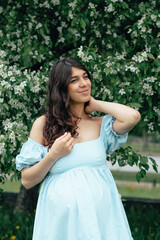 Portrait of a beautiful young pregnant woman in blooming apple trees.Spring,beauty,women's health concept.