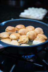 Frying homemade donuts in the kitchen, sweet dessert.