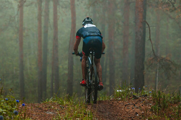 back male cyclist riding cross-country cycling, mountainbike competition race, mysterious misty...