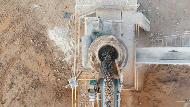 Crushing plant in quarry top view. Aerial flight over crusher in quarry. Stone crushing. Industrial production of gravel. Gravel conveyor view above. Cone type rock crusher