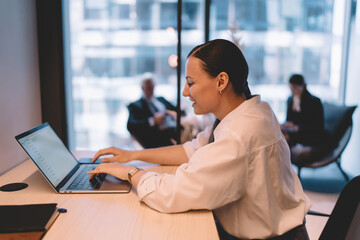 Smiling woman working on laptop in office at desk