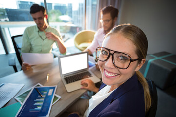 Happy businesswoman with colleagues in background
