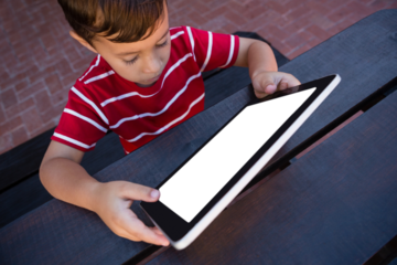 High angle view of boy using tablet while sitting at table