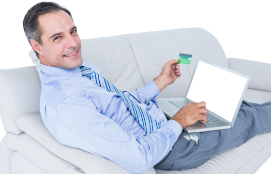 Smiling businessman with credit card and laptop on sofa