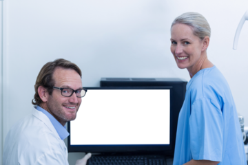 Portrait of dentist and dental assistant discussing xray on the monitor