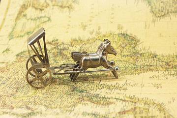 Bronze figurine with horses on background of old vintage map of world