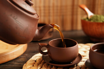 Tea Ceremony. Traditional Asian Tea Utensil, Serving Authentic Set. Person Pouring Tea from Brown Pottery Teapot to Teacup. Bamboo Tray. Lifestyle. Wellness Balance Health. Tea Brewing Equipment