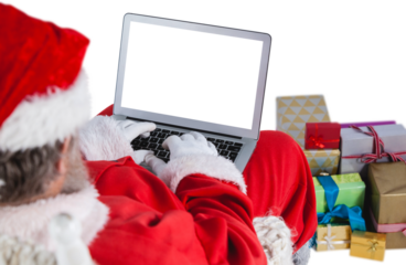Santa Claus using laptop by gift boxes