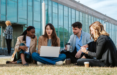 A group of four people sitting on the lawn chatting and discussing strategy outside an office...