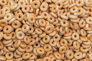 Many sweet and tasty round doughnuts, ring donuts covered with sugar. Chocolate-frosted doughnut. Symbol of sweeties, fried dough. A lot of sweet unhealthy food. Food waste, food production.