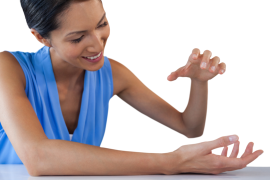 Happy businesswoman holding something while sitting at table