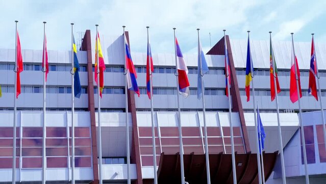 Strassbourg, France, August 2021: many national flags in front of building of international organization Council of Europe, concept of standards of law, human rights and cultural interaction