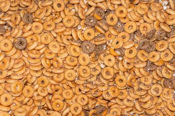 Many sweet and tasty round doughnuts, ring donuts covered with sugar. Chocolate-frosted doughnut. Symbol of sweeties, fried dough. A lot of sweet unhealthy food. Food waste, food production.