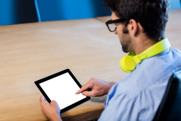 Man using digital tablet at table while sitting on chair