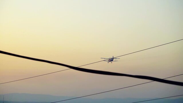 Crop duster plane fly spraying chemicals over a cotton field at sunrise, sunset