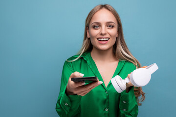 cute stylish attractive blonde girl with headphones and smartphone on a blue background