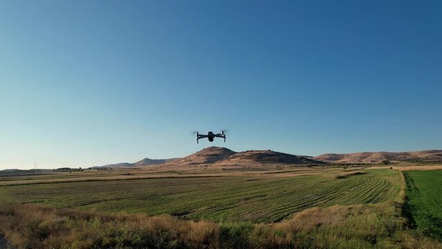 Drone analize agriculture field at sunset, sunrise. Technology used for various fields like research analysis, safety, rescue, terrain scanning technology, monitoring soil hydration