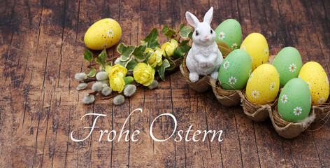 Grußkarte Frohe Ostern: Ostereier und Deko Hase auf rustikalem Holz mit der Inschrift Frohe Ostern.