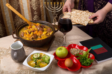 A woman at the table laid for the Passover seder holds matzah in her hands.