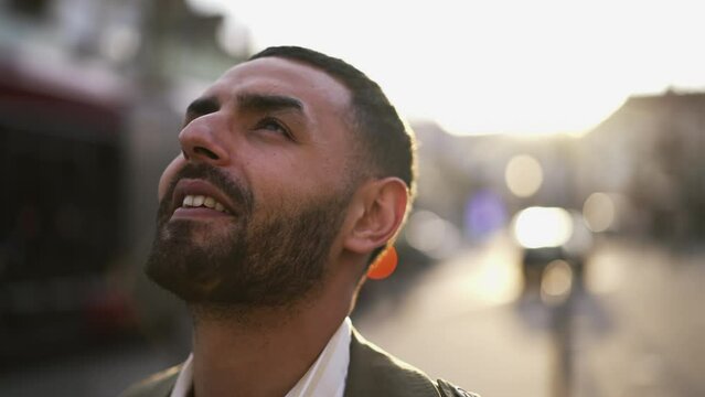 Portrait of a pensive happy Middle Eastern Man gazing at sky with HOPEFUL expression standing in steet