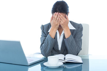 Upset businesswoman covering face at desk