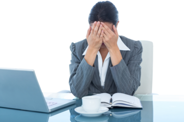 Upset businesswoman covering face at desk