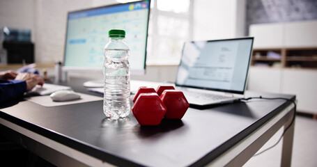 Naklejka premium Water Bottle And Dumbbell In Front Of Businessperson Working