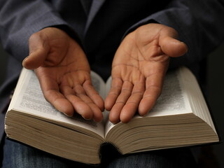 praying to God with hand on the bible on lack background stock photo