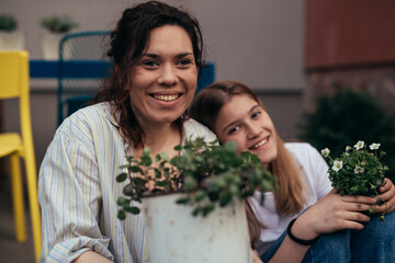 Portrait of a happy mother with her daughter in the yard planting pants together