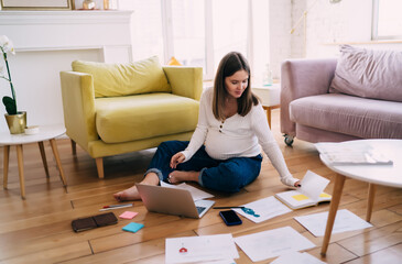 Pregnant woman working on project with laptop and documents