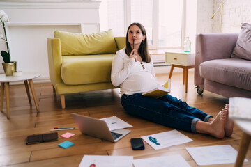 Pregnant woman thinking of new project ideas on floor