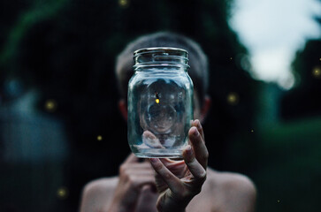 Boy Holding a Jar with Fireflies - obrazy, fototapety, plakaty