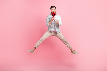 Fototapeta na wymiar Full length photo of cheerful funky guy dressed teal shirt jumping high screaming loudspeaker isolated pink color background
