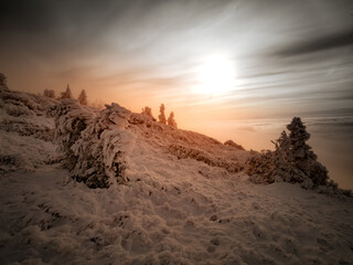 Scenic landscape with a view from a mounatin range to the valley filled with low clouds and fog during temperature inversion