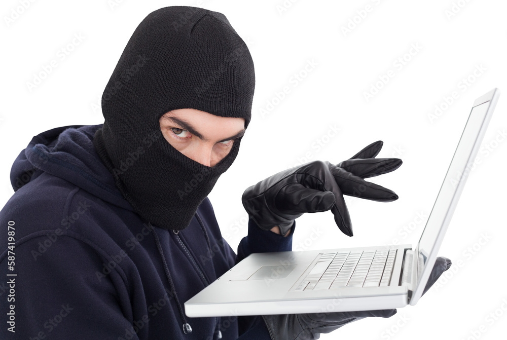 Poster hacker in balaclava standing and typing on laptop