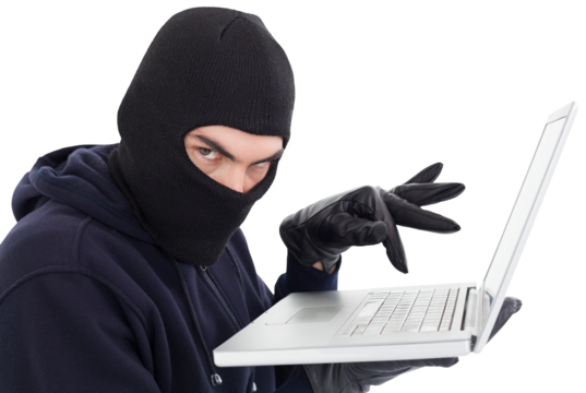 Hacker in balaclava standing and typing on laptop