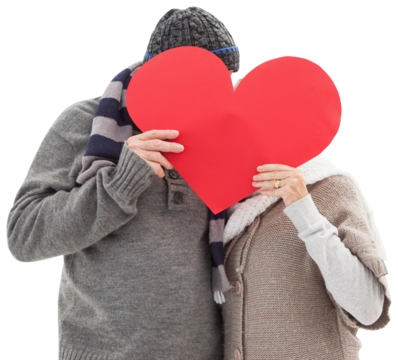 Happy mature couple in winter clothes holding red heart