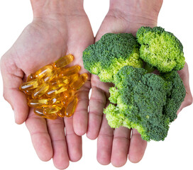 Cropped hands holding broccoli and vitamin pills