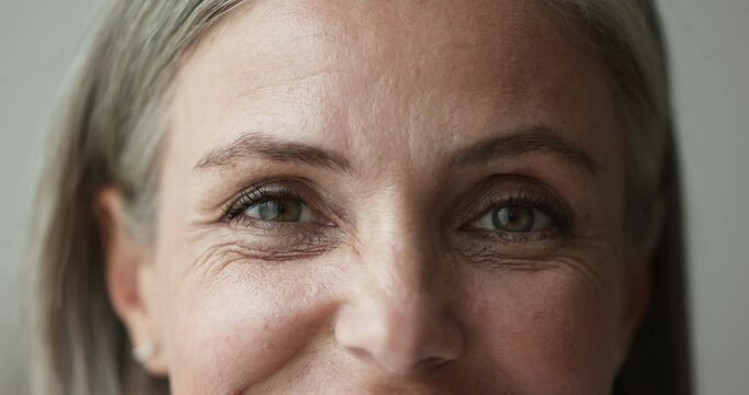 Close up front view upper face part of mature attractive woman blinks look at camera, watching, staring at cam, advertise eyesight vision laser correction procedure, lenses, ophthalmology, eye-care