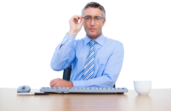 Handsome businessman adjusting glasses while sitting at desk