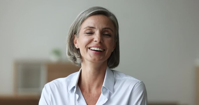 Head shot happy attractive businesslady staring at cam pose indoors. Portrait of mature woman having beautiful european appearance, positive mood, look at camera revealing wide toothy perfect smile