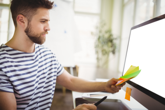 Man looking at sticky notes in office