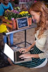 Female florist sitting and using laptop