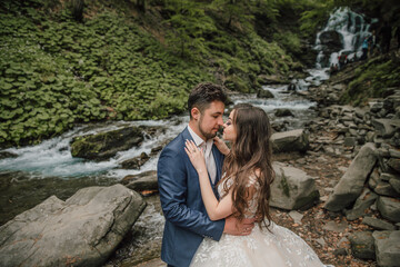 Portrait of a happy bride and groom near a waterfall. Bride and groom. Wedding photo session in nature. Photo session in the forest of the bride and groom.