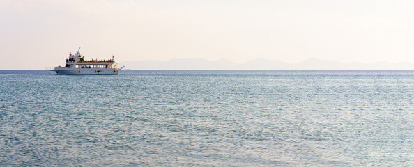 Sea and clear sky landscape. Sightseeing boat on distant. Horizontal photo image can be used as printed canvas, website banner, social media post. 